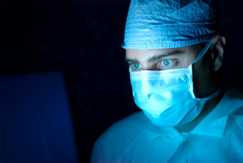 Surgeon wearing a mask and using a computer.
